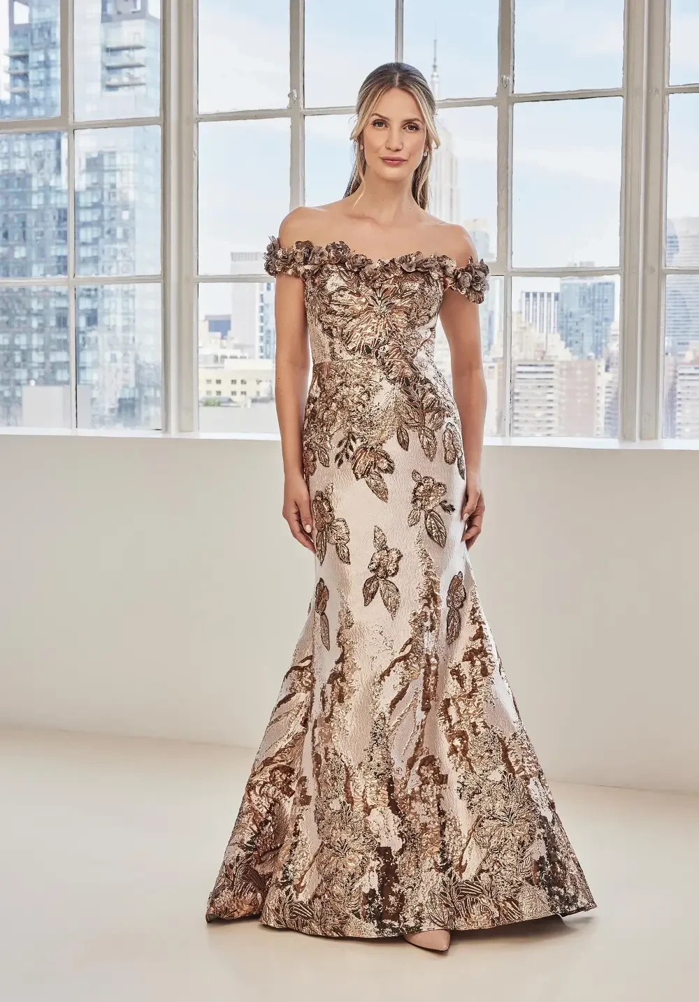 model is wearing an off the shoulder gold mothers gown