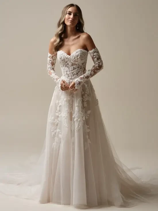 Model is wearing a strapless a-line lace and tulle wedding dress with detachable off the shoulder long lace sleeves 