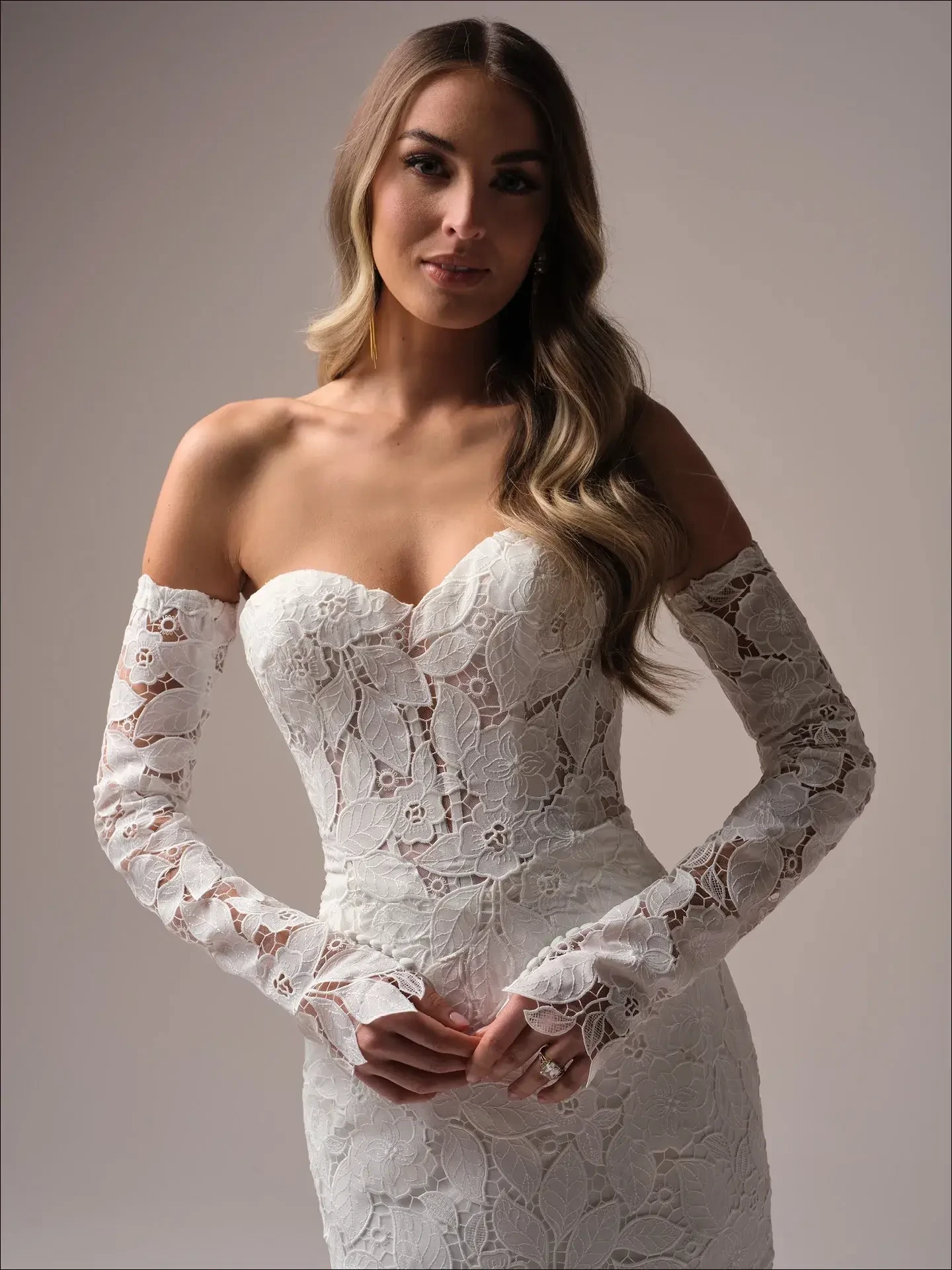 model is wearing a strapless wedding dress with off the shoulder lace long sleeves 