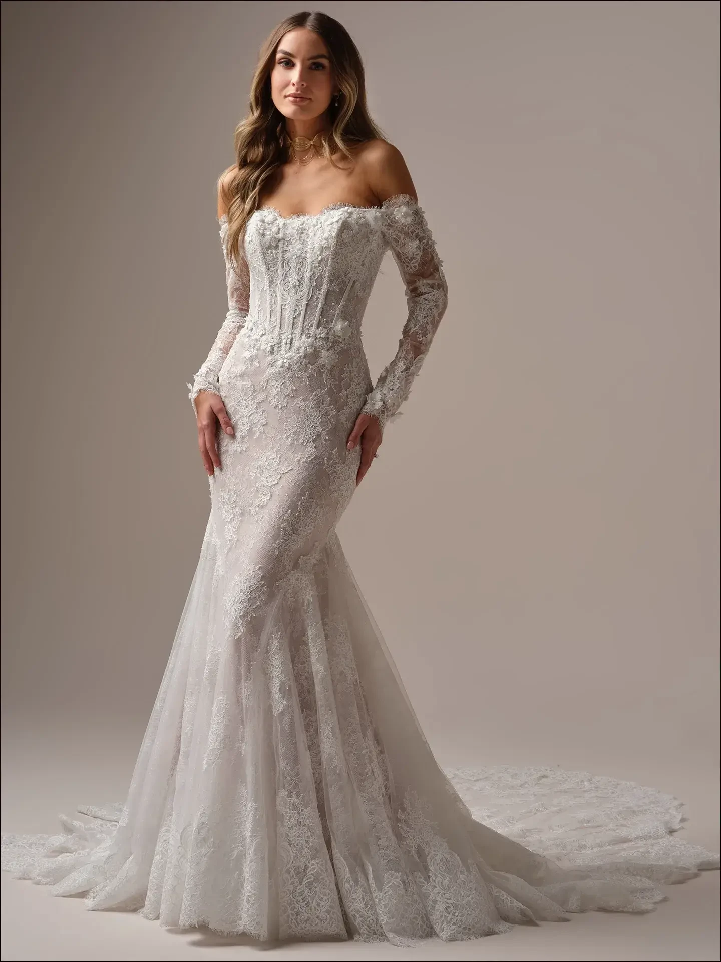 model is wearing a lace off the shoulder long sleeve fit and flare wedding dress