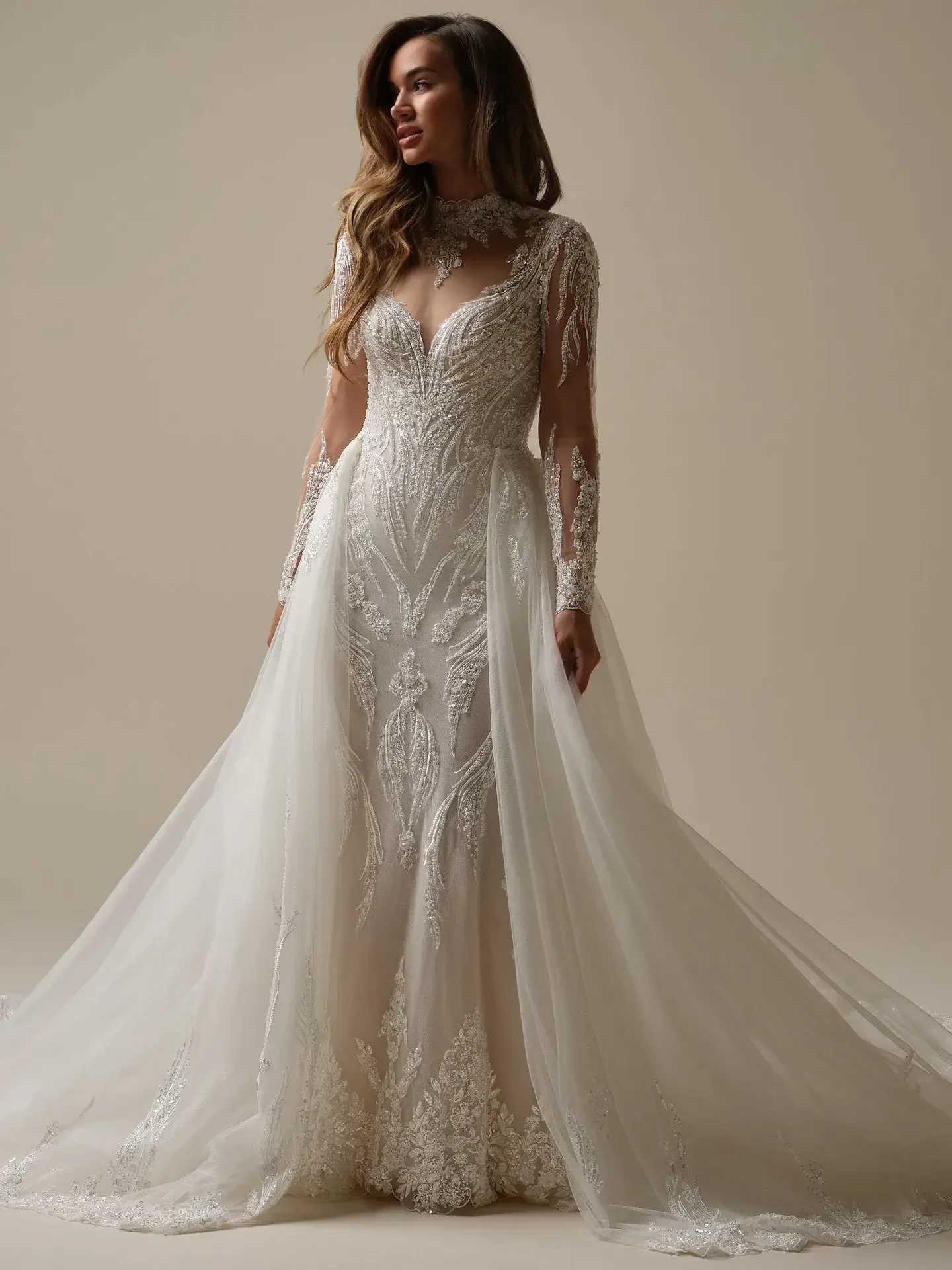 model is wearing a fit and flare glamorous wedding dress with an overskirt
